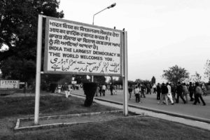 A sign at the border with Pakistan in the state of Punjab featuring the same message written in three different languages (Hindi/Urdu, Punjabi, and English) and four different scripts from the top down: Devanagari (Hindi), Punjabi, Roman (English), and Perso–Arabic (Urdu)