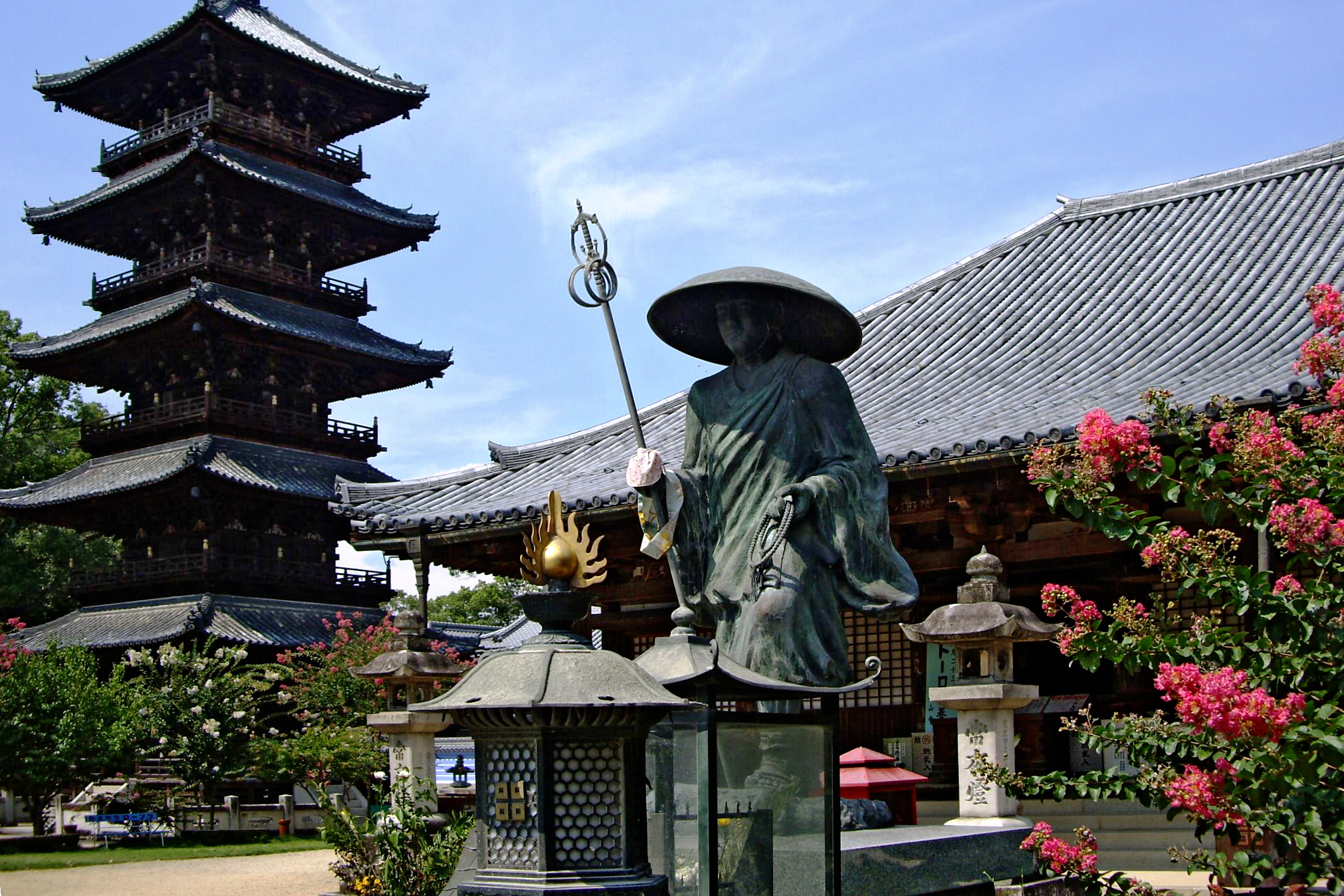 Bronze statue of a Buddhist priest in front of a Japanese temple.