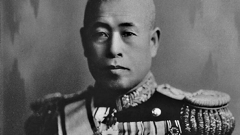 A portrait painting of middle-aged Yamamoto, depicting him from the head to the shoulders. Yamamoto has a shaved head and is seen gazing thoughtfully towards the viewer. He is dressed in a full military uniform, adorned with various army badges.