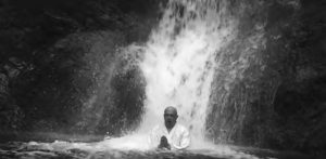 Image of a monk sitting under the waterfall 